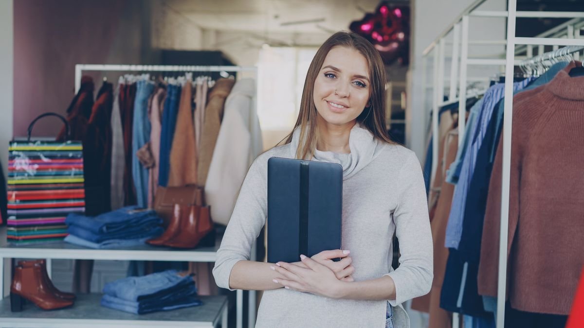 Winkeleigenaar lacht met een tablet in de winkel